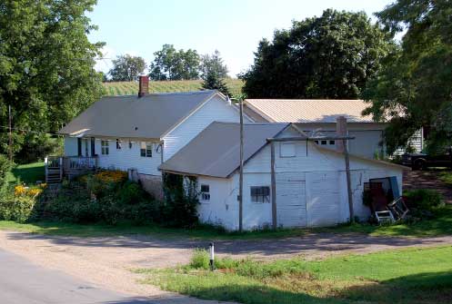 Figure 8. Former cheese factory located in the Town of York in Green County, which is now being used as a residence. The lower part of this building near the large chimney is where cheese making occurred, while residential quarters were located in the upper floor. Cheese was often stored in the basement nestled in the slope of such buildings for aging.